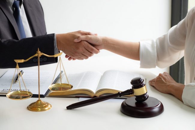 lawyer consultant with client shaking hands together with contract agreement.